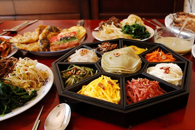 People in Korea celebrating Chuseok, the Korean harvest festival similar to Thanksgiving, with traditional clothing, food offerings, and family gatherings.