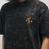 Person wearing a black acid-washed t-shirt with a small graphic of a Korean tiger and 광복 on a plain background