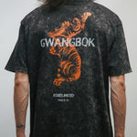 Person wearing a black t-shirt with a tiger graphic and 'GWANGBOK' text on the back.