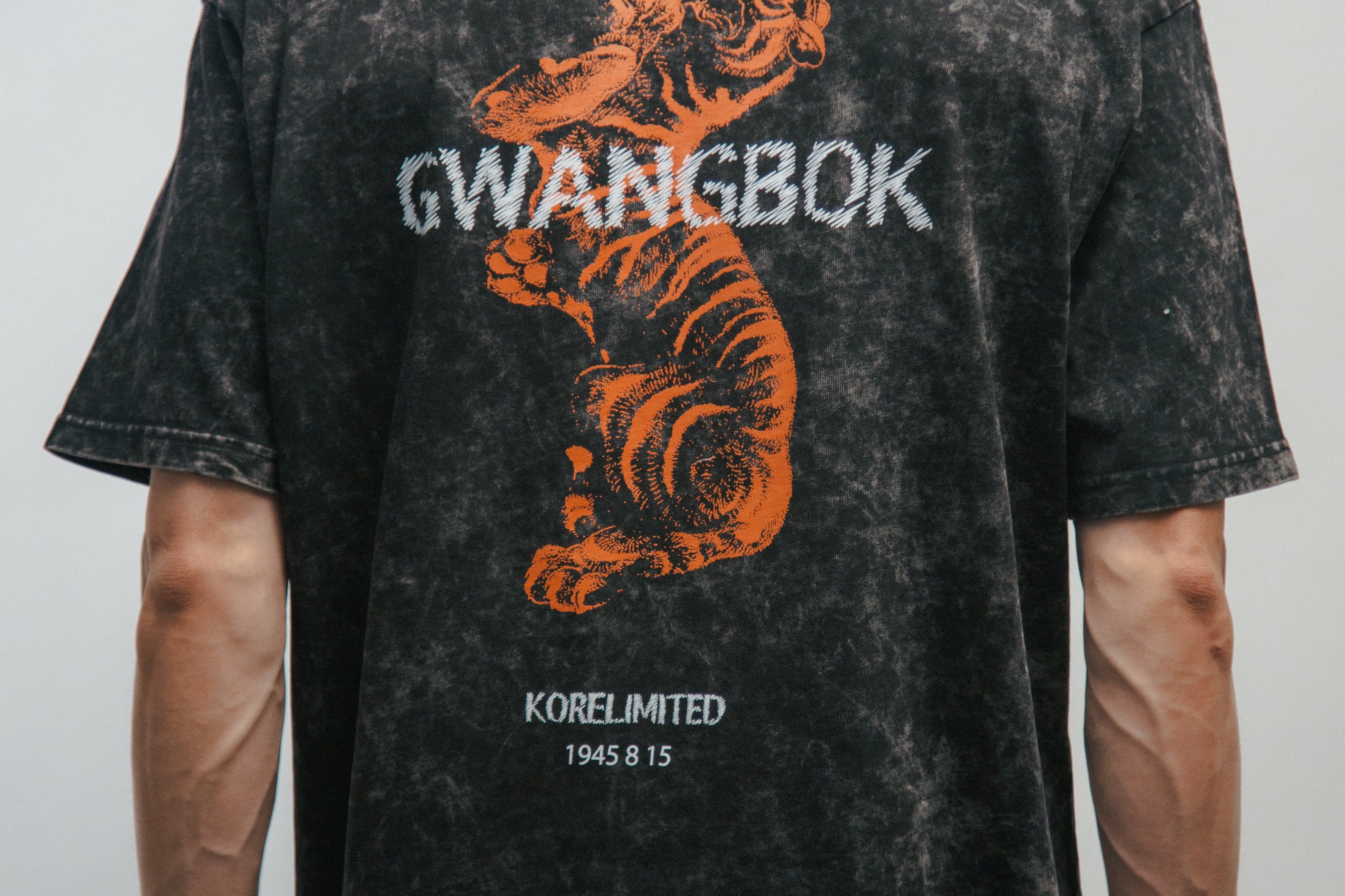 Person wearing a black t-shirt with a tiger graphic and 'GWANGBOK' text on the back.