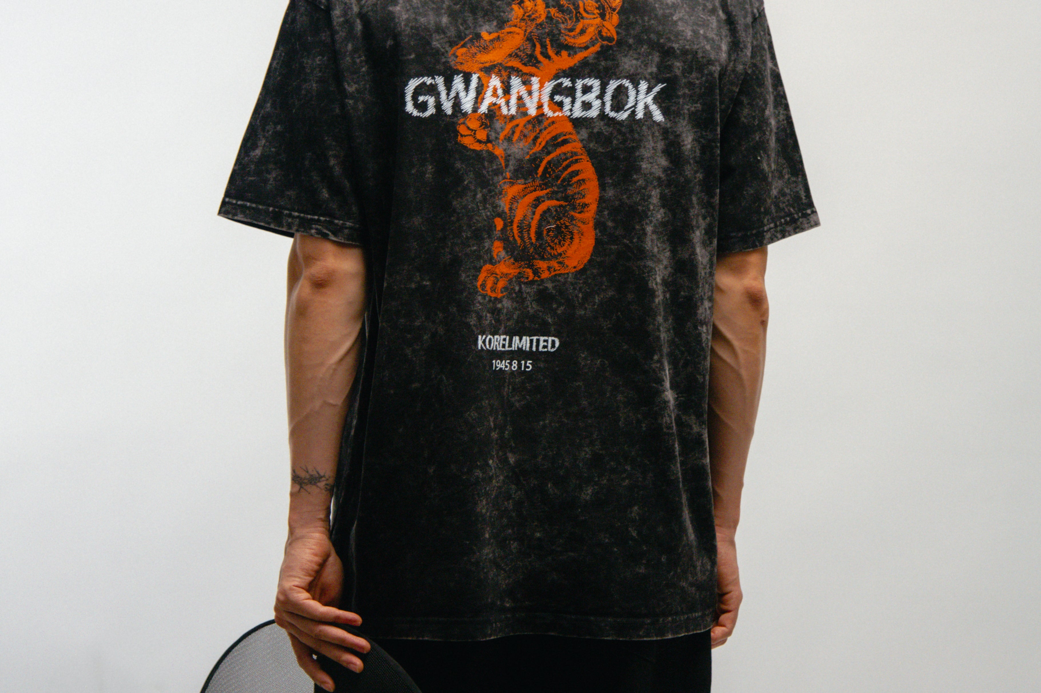 Person wearing a black t-shirt with 'GWANGBOK' design and an orange Korean tiger on the back, standing against a white background.