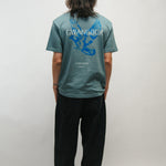 Person wearing a teal t-shirt with a blue dove logo and 'Gwangbok' on the back against a plain background