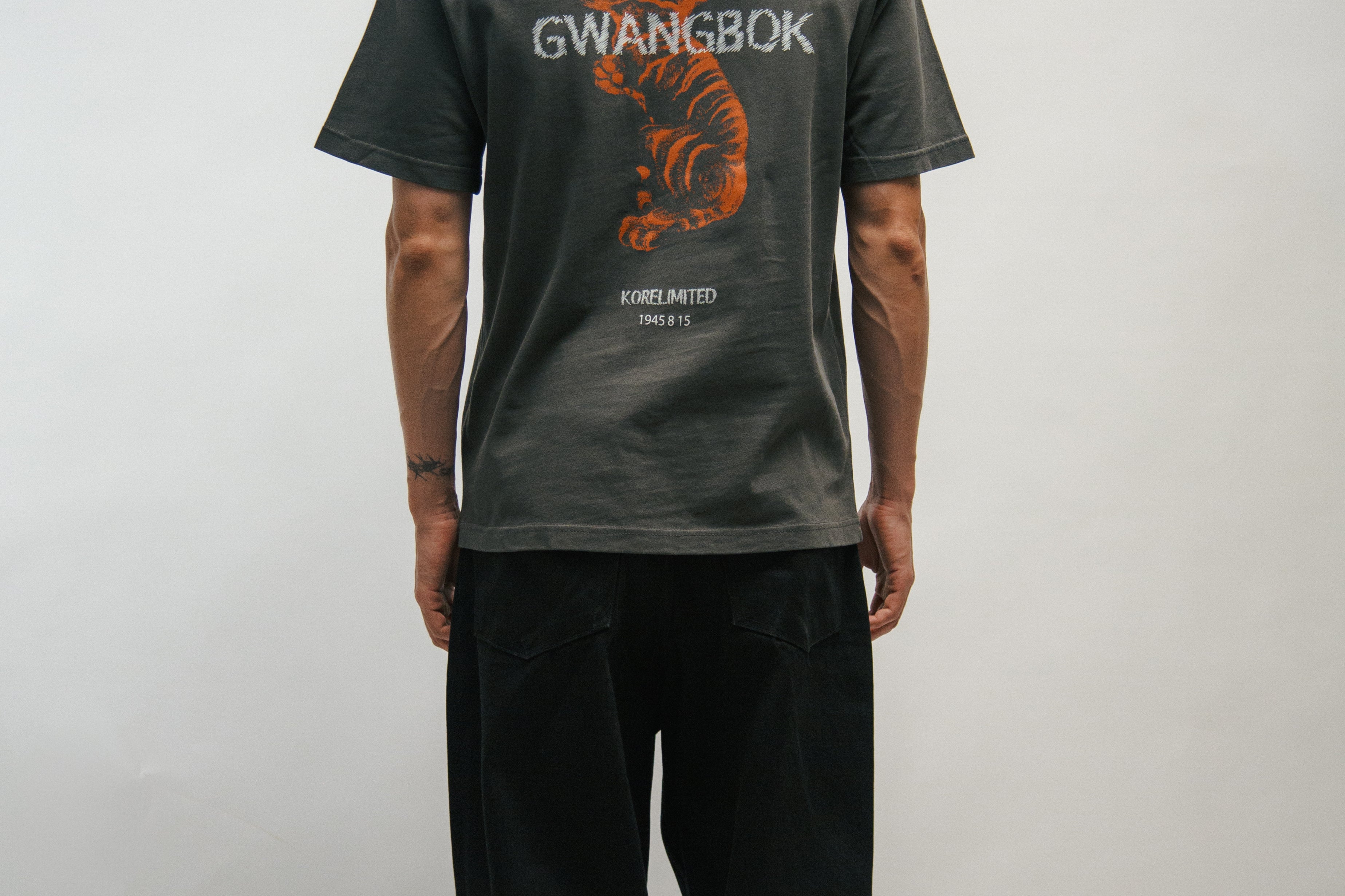 Person wearing a gray t-shirt with 'GWANGBOK' design and an orange Korean tiger on the back, standing against a plain background.