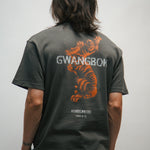 Person wearing a dark gray t-shirt with orange Korean tiger design and text GWANGBOK on the back, against a plain background.
