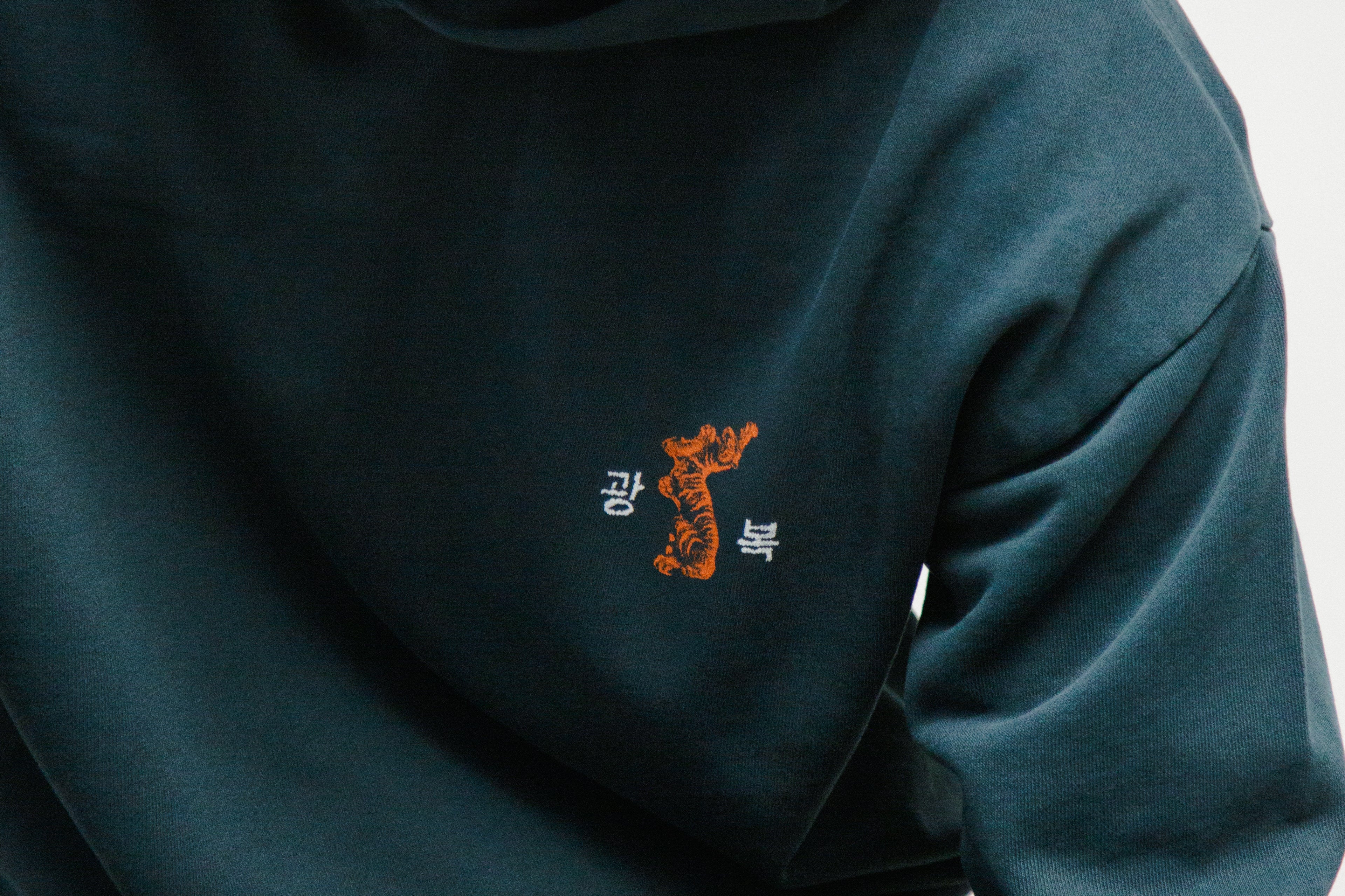 Person wearing a navy hoodie with a small tiger graphic and 광복 text on the chest.