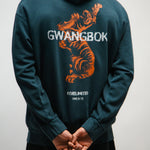 Person wearing a teal hoodie with a Korean tiger graphic and 'GWANGBOK' text on the back.