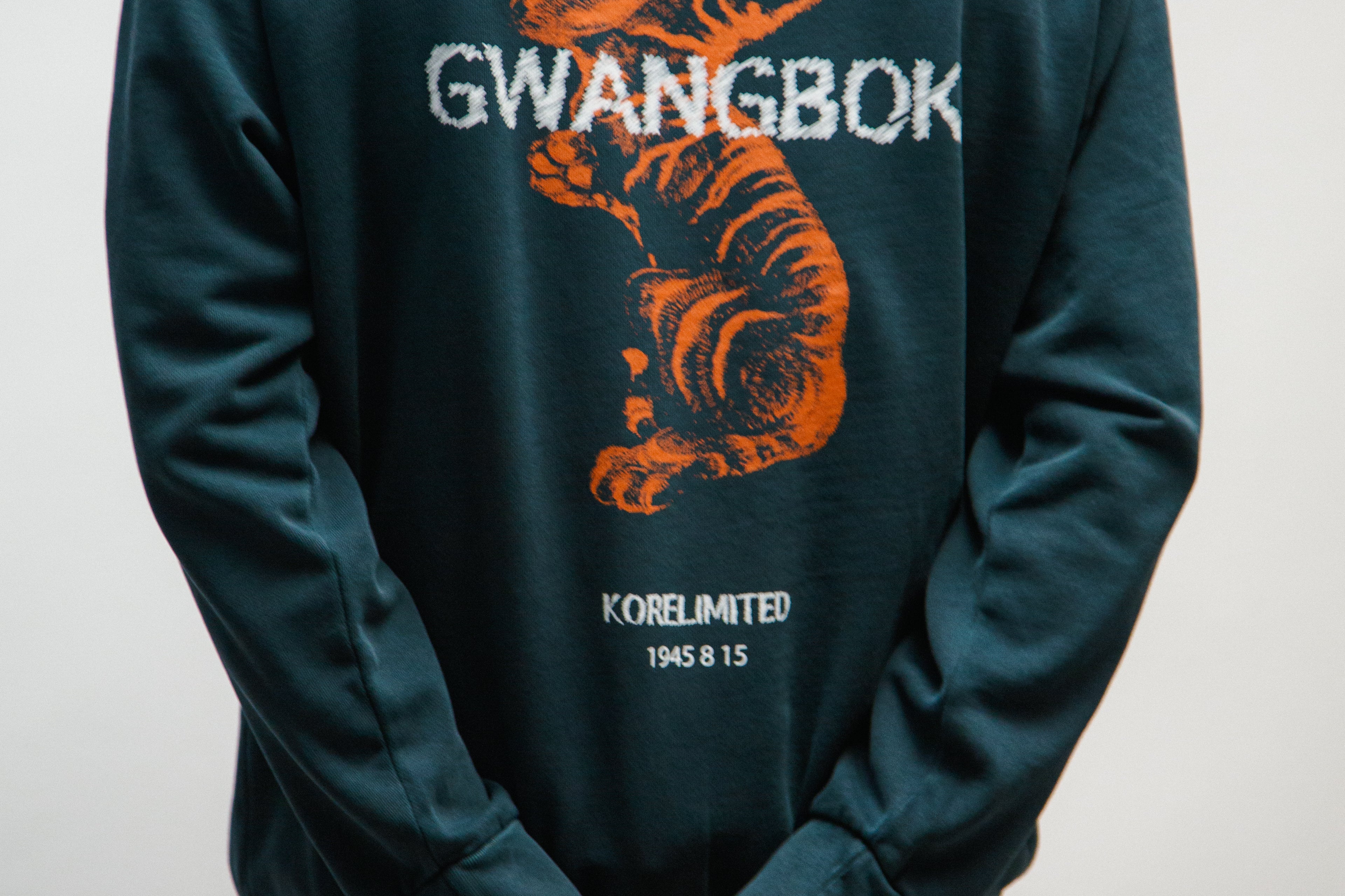 Person wearing a teal hoodie with a Korean tiger graphic and 'GWANGBOK' text on the back.