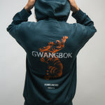 Person wearing a teal hoodie with a Korean tiger design and 'GWANGBOK' text on the back, against a plain background.