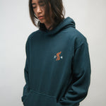 Person wearing a teal hoodie with a small Korean tiger graphic and Korean characters 광복 on a plain background