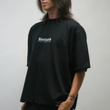 Person wearing a black t-shirt with a KORELIMITED logo on a plain background