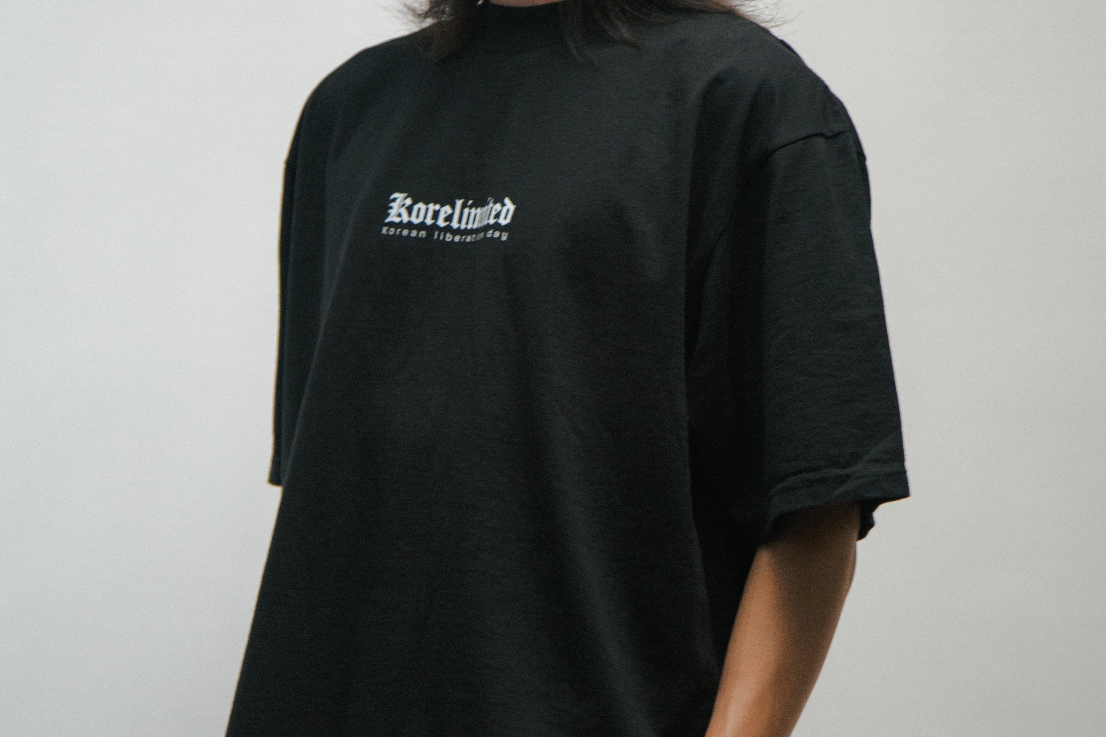 Person wearing a black t-shirt with a KORELIMITED logo on a plain background