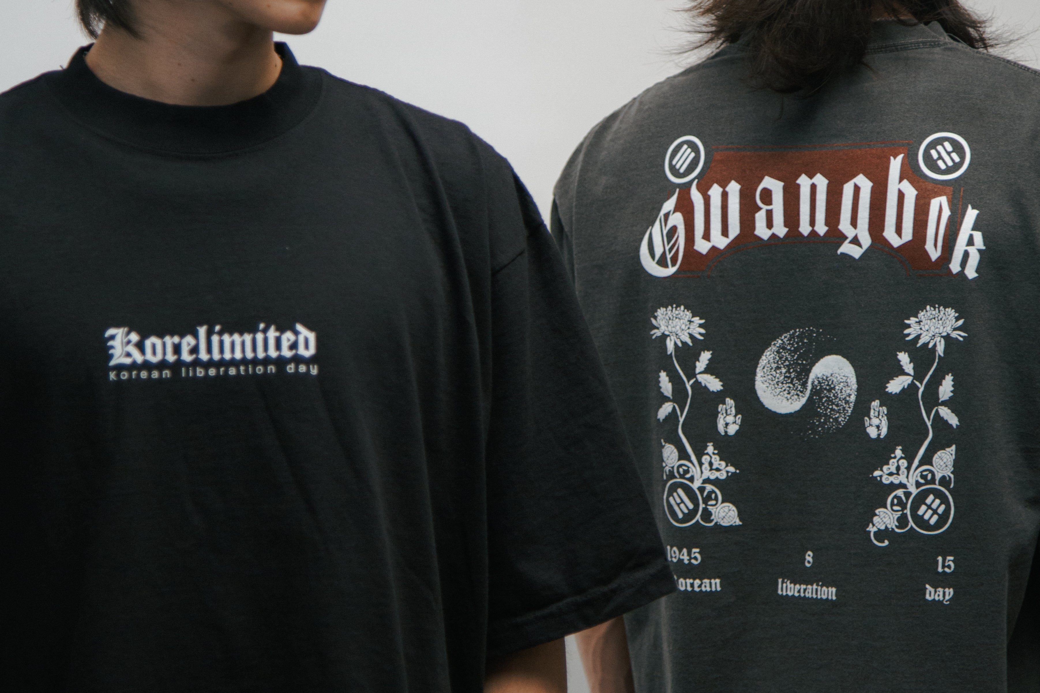 Two people wearing black drop shoulder t-shirts with front and back of KORELIMITED Gwangbok shirts.