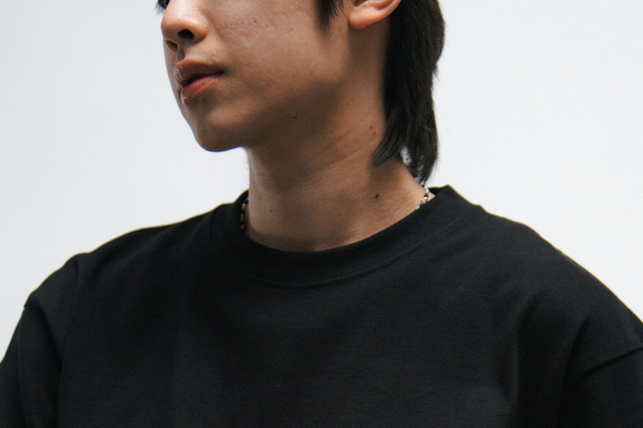 Person wearing a black t-shirt with a blue bird logo and a blue bandana on a white background