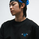 Person wearing a black t-shirt with a blue bird logo and a blue bandana on a white background