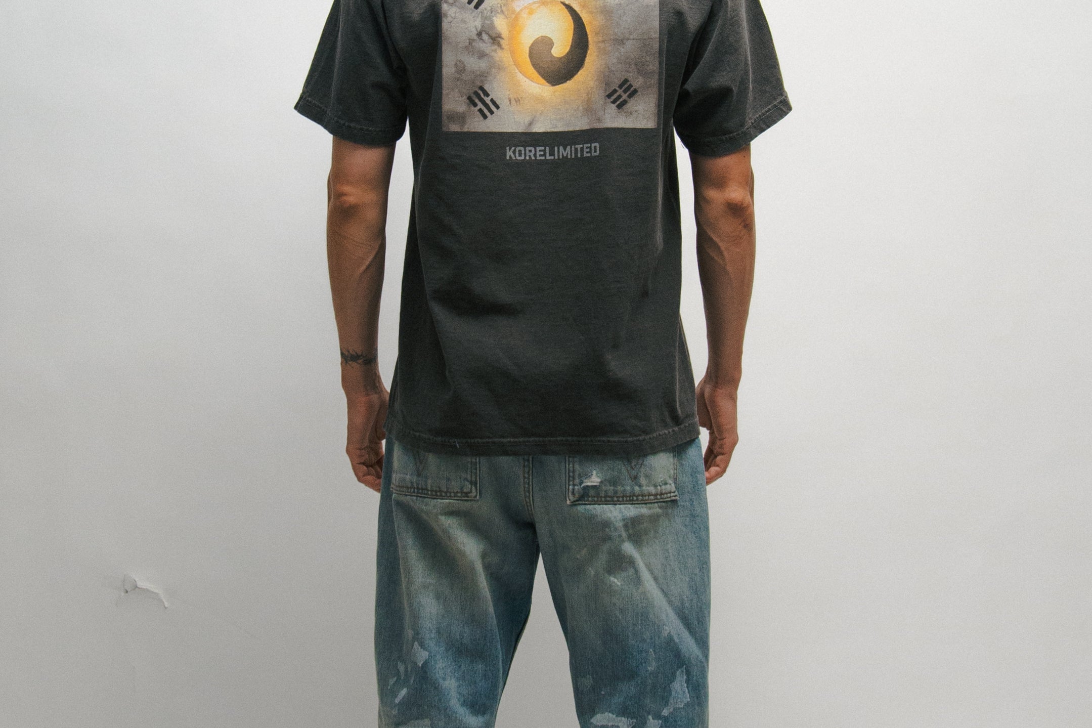 Person wearing a black t-shirt with a Korean Flag graphic design on the back, standing against a plain background.