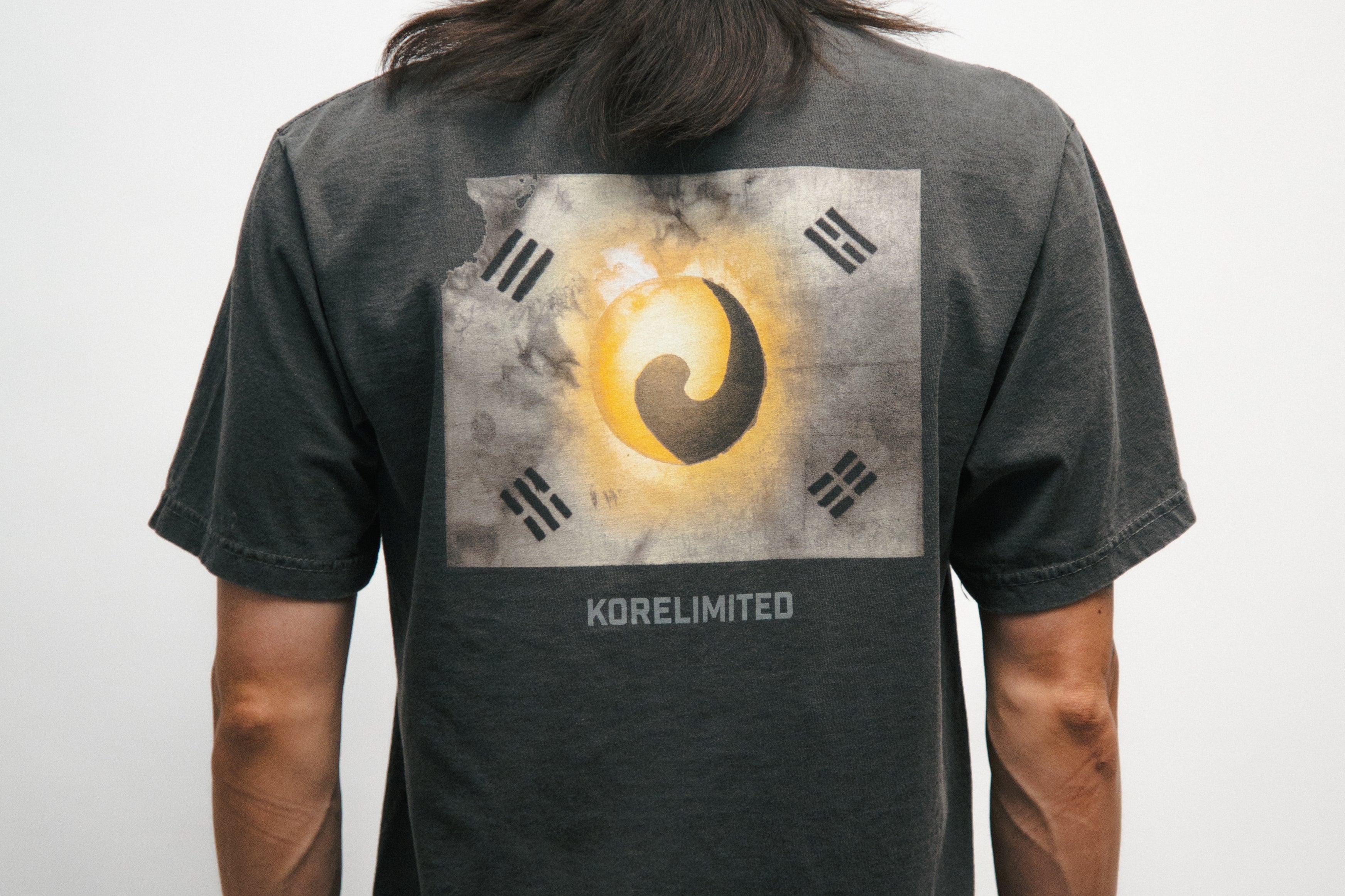Person wearing a black t-shirt with a Korean Flag graphic design on the back, standing against a plain background.