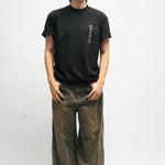 Person wearing a black t-shirt and brown pants on a white background