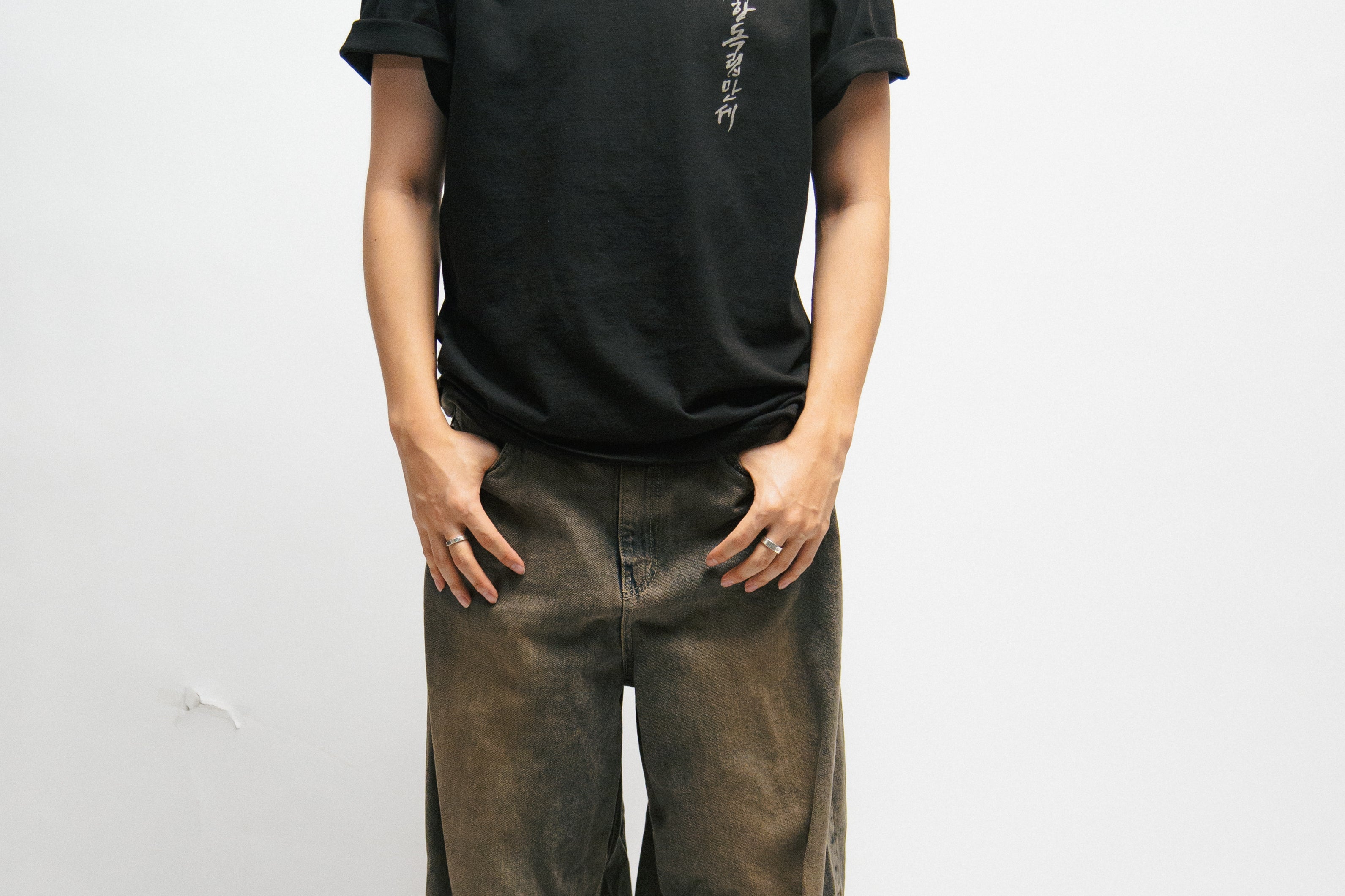 Person wearing a black t-shirt and brown pants on a white background