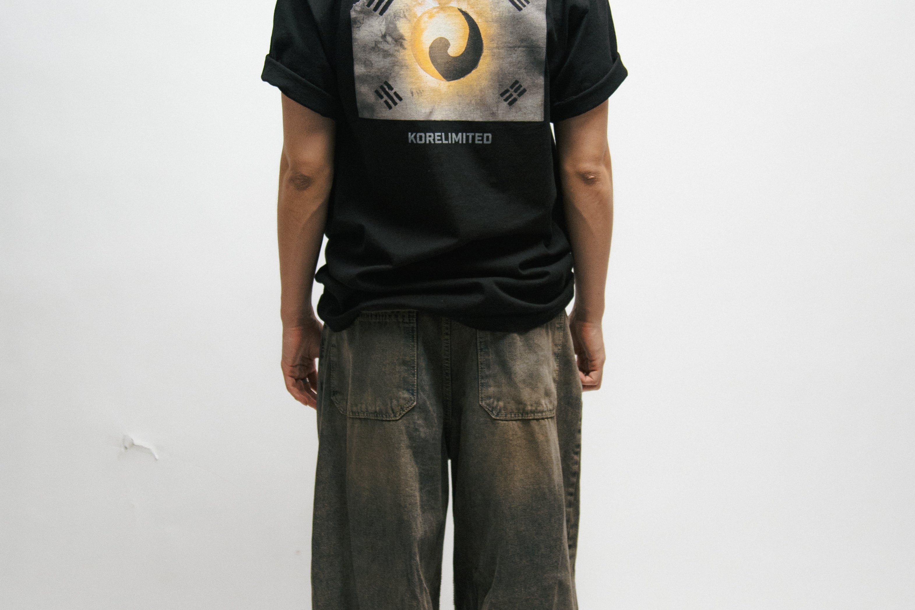 Person wearing a black t-shirt with a Korean Flag graphic design on the back, standing against a white background