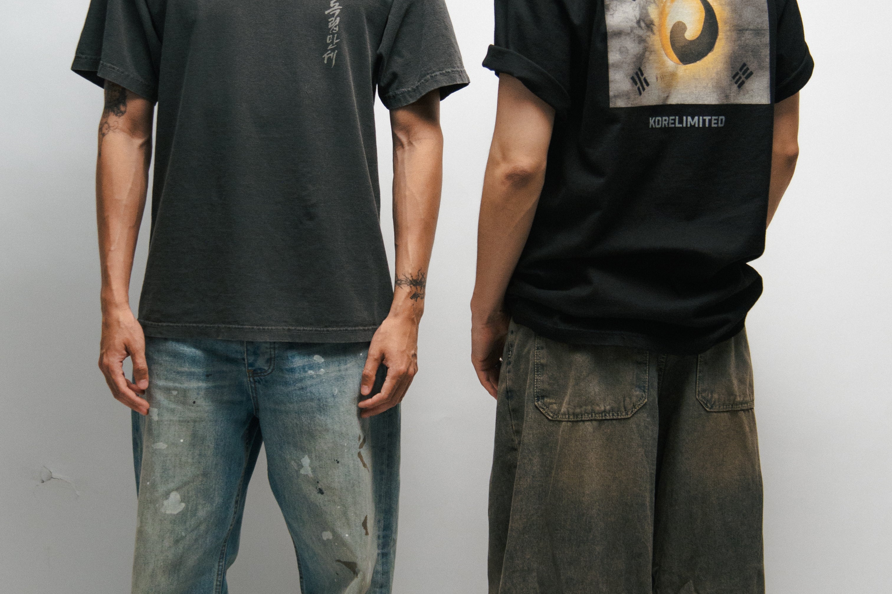 Two male models wearing black and dark grey t-shirts with Korean Flag graphic designs, one facing forward and one facing backward.