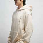 Male person wearing beige hoodie with Korean font in the front